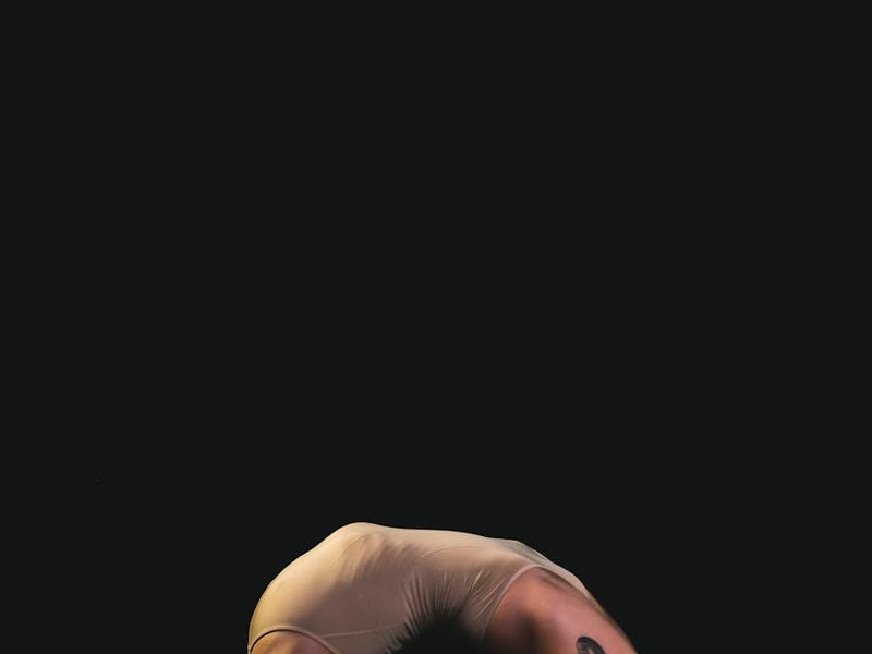 Person performing a slow yoga movement in a dark studio